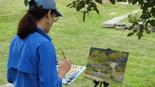 An artist painting painting in a field.