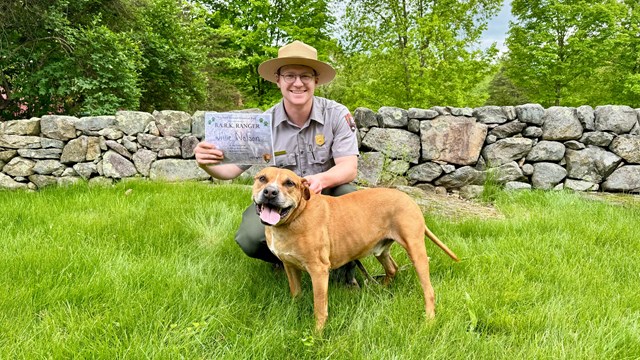 Park Ranger holding up a BARK Ranger Certificate with a dog at Weir Farm