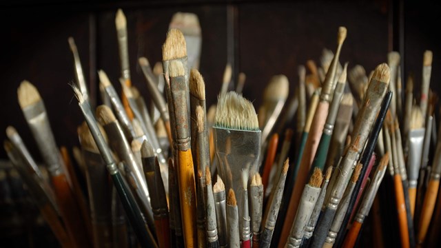 A close-up image of a group of various size paint brushes.