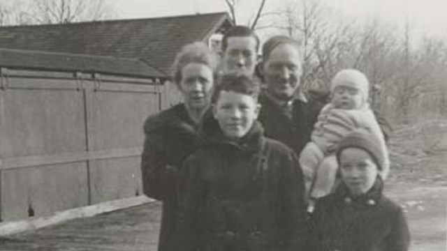 A black and white photo of six people (two children, a woman, a baby, and two male adults. 