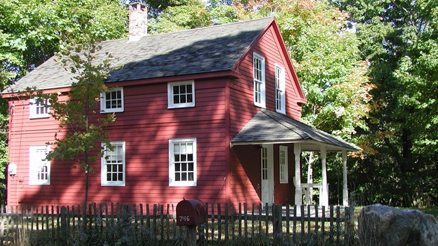 A red building with white trim and a wooden fence in the foreground.