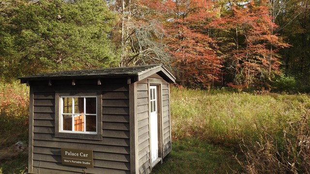 A small wooden building on stilts with a small door and window.