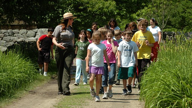A group of students follows a Ranger on a dirt path.