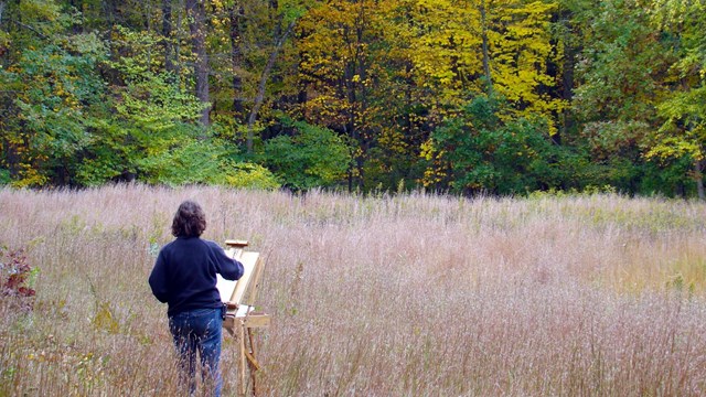 Artist painting in a field in Autumn