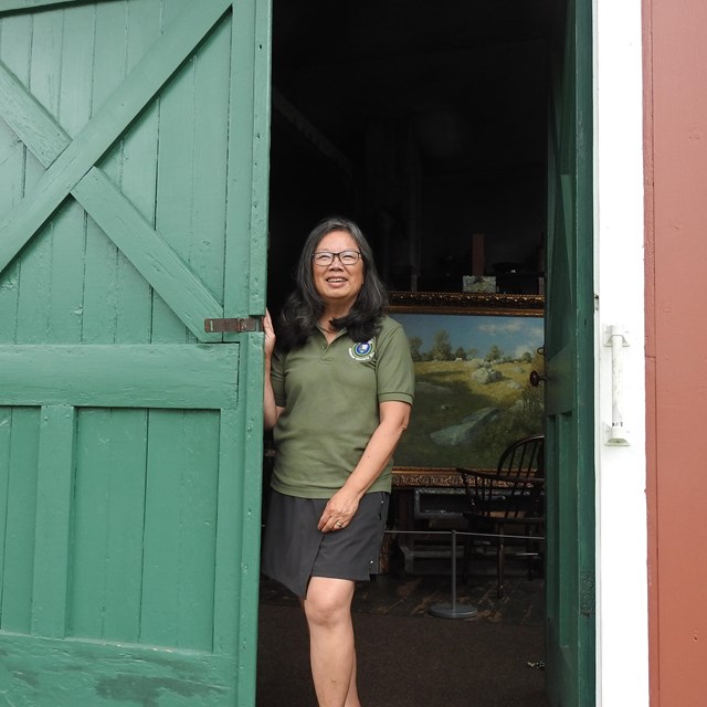A volunteer standing in an open doorway with a painting behind them.