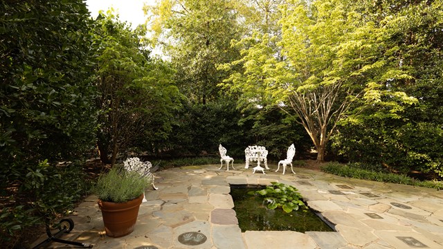 A patio area walled in by greenery.