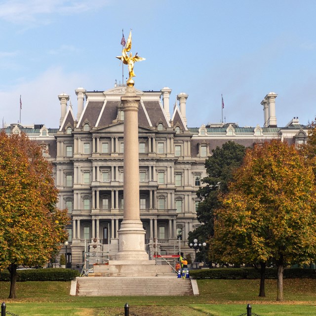 A tall column with a gold statue of a winged figure on the top.