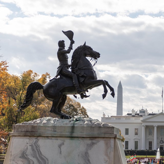 A statue of General Andrew Jackson on a galloping horse waving hat in the air.