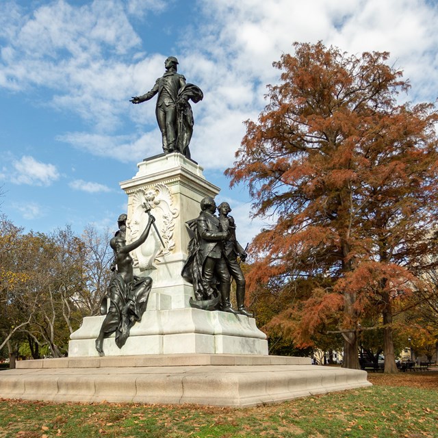 A bronze statue of Lafayette standing with hand outstretched.