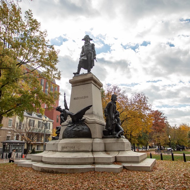 A bronze sculpture of Thaddeus Kosciuszko atop a stone plinth with an eagle and soldiers.