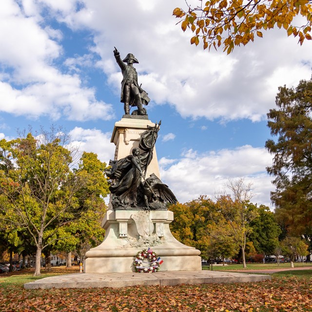 Bronze statue of Gen. Rochambeau in Revolutionary War attire atop a plinth.