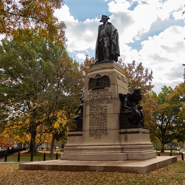 Bronze statue of a man in winter army uniform on a stone plinth.