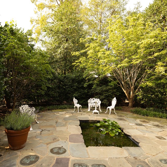 A patio area walled in by greenery.