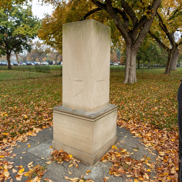 A square stone column with engravings.
