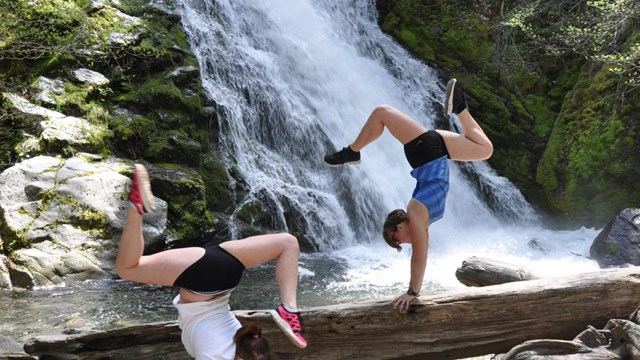 Whiskeytown Falls cascade. Two women doing yoga poses at base of falls.