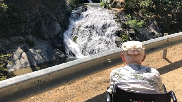 Man in wheelchair looking a Crystal Creek Falls cascade.