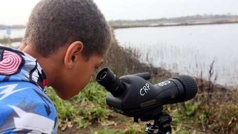 A young boy looks at the lansdcape through a telescope