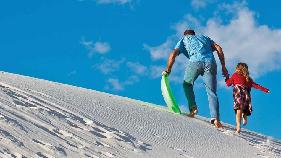 Visitor enjoying sledding on dune.
