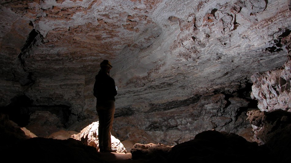 explorer shines light in a cave