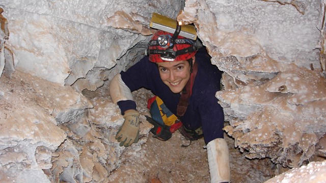 A caver squeezes through a space in the cave.