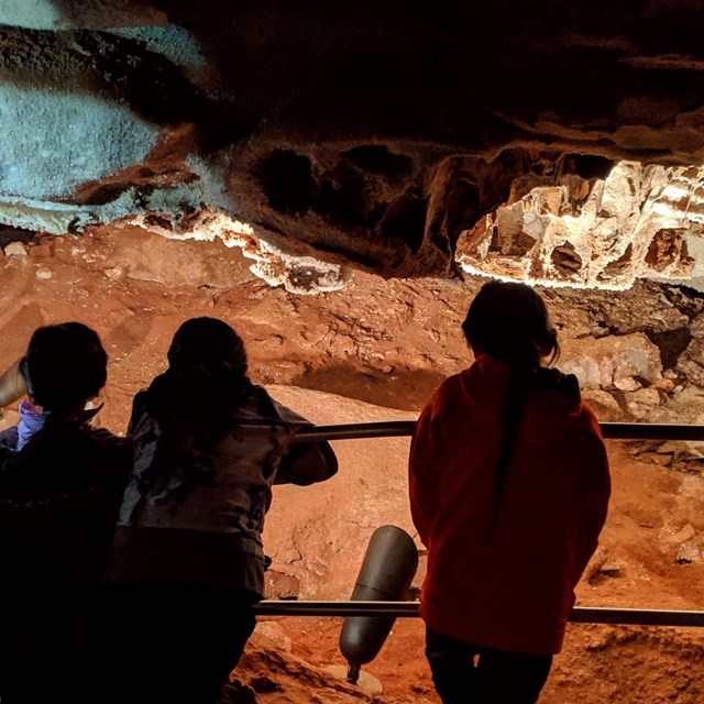 Kids looking at cave formations back-lit by the cave lighting