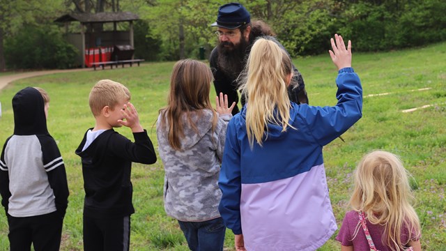 A man dressed in union uniform speaks to a line of children