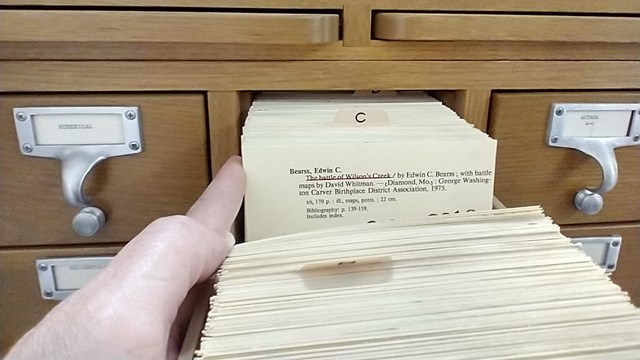 Hand sorts through old filing drawer. 