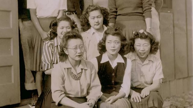 A group of Asian American men and women outside a wooden building