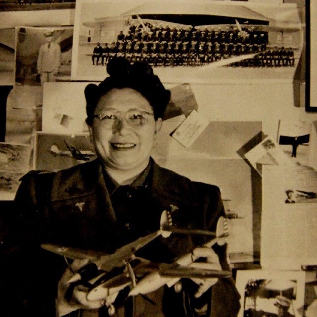 Dr. Margaret Chung with a Lockheed P-38 Lightning model and photos of recruits, public domain.