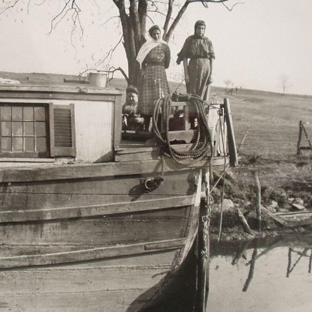 Women stand on a canal boat. NPS photo. 