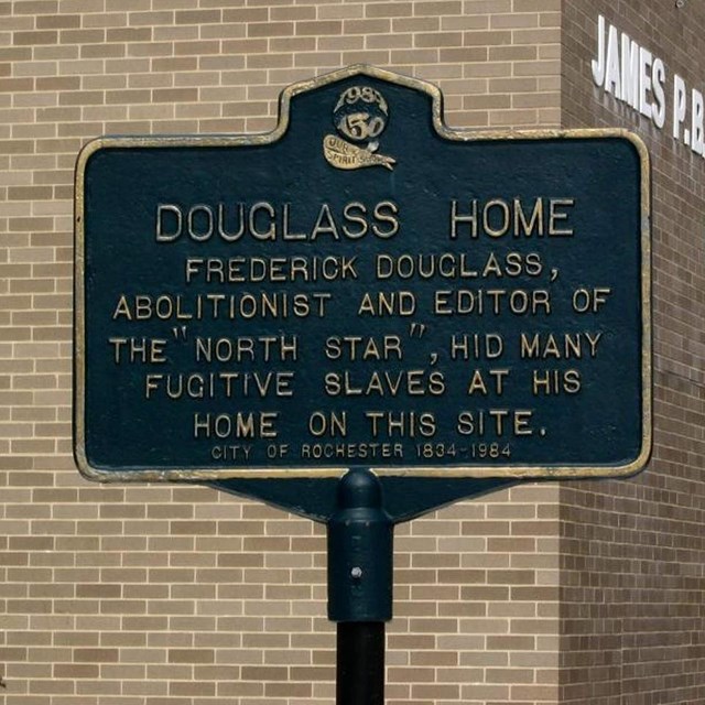 An historic marker stands outside a school at the former location of Frederick + Anna Douglass' home