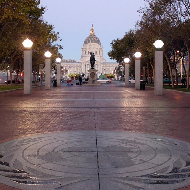 Brick walkway lined with round lights, with domed building in background.