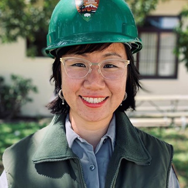 A woman in a hard hat smiles into the camera