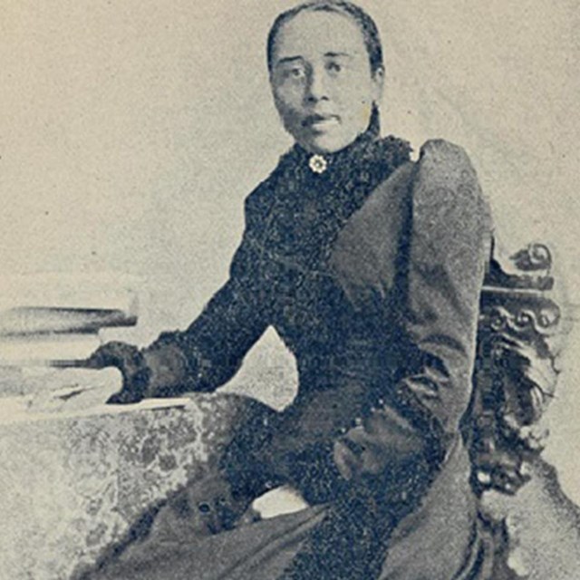 Black and white photo of Anna Julia Cooper seated at a table