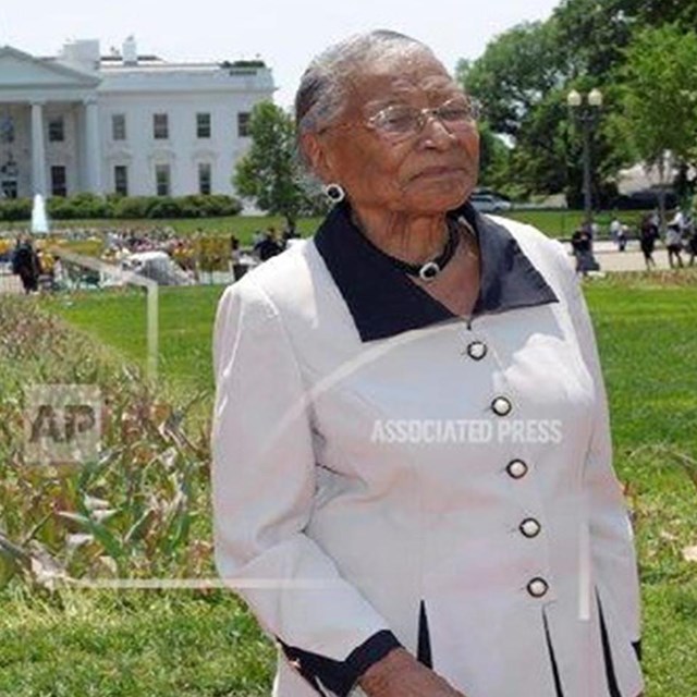 Color photo of Mrs. Taylor standing near the White House