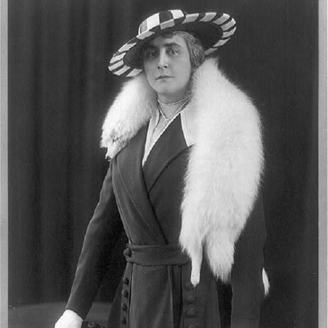 Woman with large hat and white fur stole.