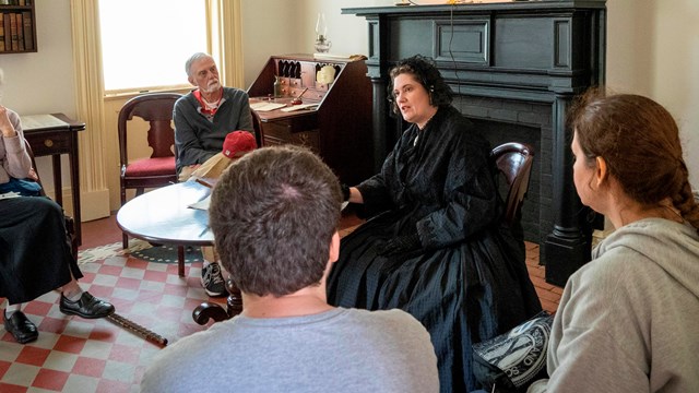 A living historian dressed as Elizabeth Cady Stanton sits and speaks to visitors.