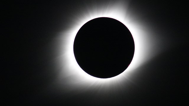 A black circle surrounded by a halo of white light.