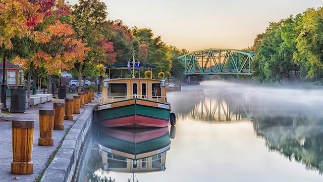 A canal boat sitting alongside a dock in autumn