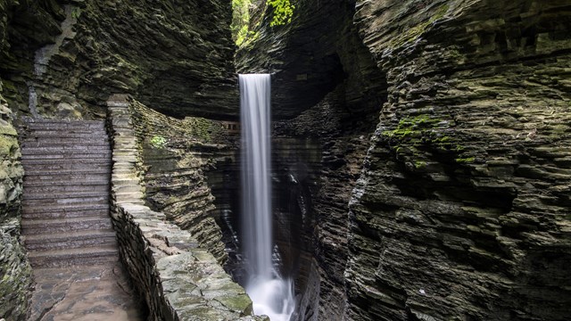 A waterfall and a stone staircase carved into a stone gorge.