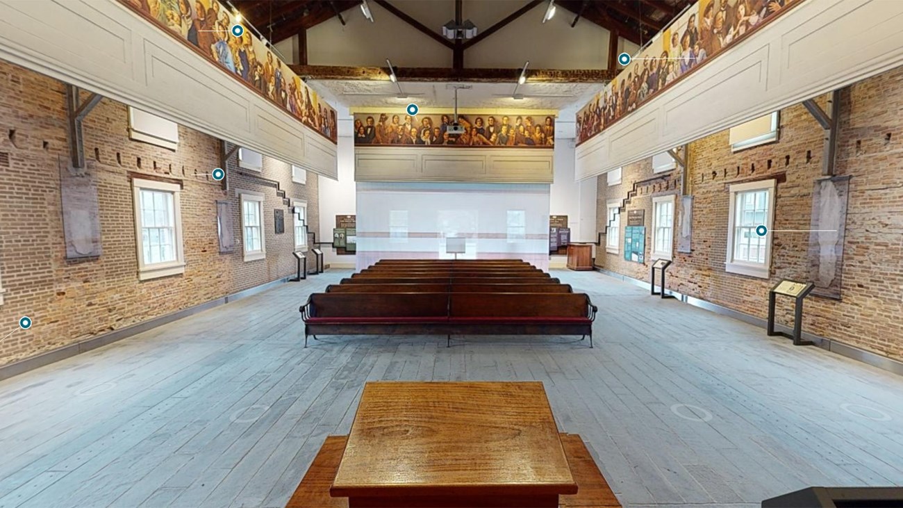 A wide-angle view of the Wesleyan Chapel interior, looking from the podium out to the rows of pews.