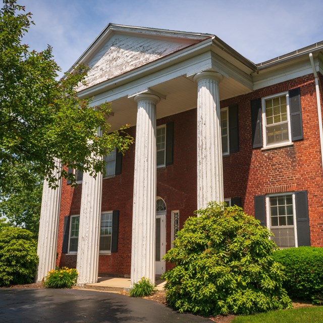 A two-story red brick house with a white columned portico.