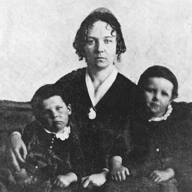 A woman sitting with two young boys