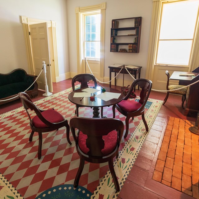 A wide angle view of the M'Clintock parlor, furnished with period furniture.