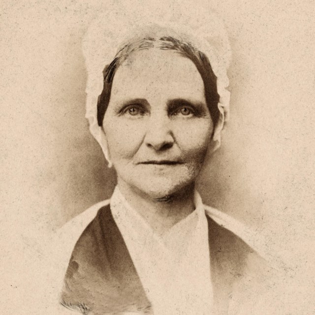 A woman in a bonnet looking directly at the camera