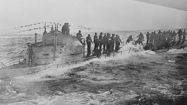 German submariners stand on the deck as waves crash around them.