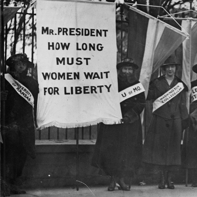 Suffragettes picket outside the White House fence.