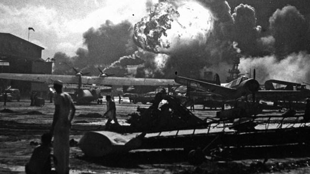 pearl harbor, black and white photo of men watching planes on ground being bombed