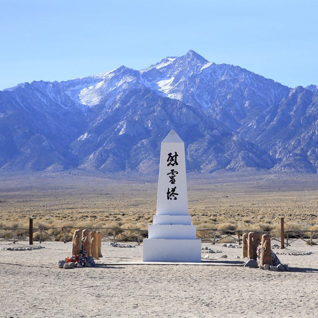 White obelisk against mountain backdrop and blue sky