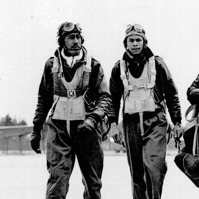 4 African American airmen walk down a runway; B&W photo